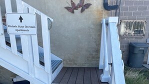 Un conjunto de escalones blancos de madera que conducen a la entrada de un edificio, con un letrero que indica 'Historic Stays On Main Apartments'.