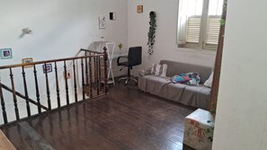 Een kamer met een houten trap, een bank, een stoel en een klein tafeltje.