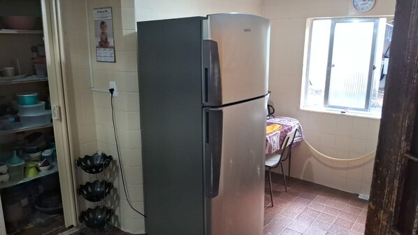 A compact kitchen with a refrigerator, a window with a view, and a table with chairs.