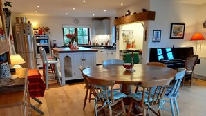 A modern kitchen with a central island, wooden dining table, and chairs. - MOYNISH MOR MULRANNY, family friendly in Mulranny, County Mayo (WESTPORT)