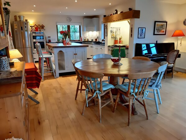 A modern kitchen with a central island, wooden dining table, and chairs.