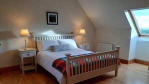 A bedroom with a wooden bed, white bedding, two bedside tables with lamps, a radiator, and a skylight. - MOYNISH MOR MULRANNY, family friendly in Mulranny, County Mayo (WESTPORT)