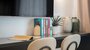 A modern room with a flat-screen TV mounted on the wall, a small potted plant, decorative vases, and a row of books on a shelf. - Downtown Bucharest Studio Close to Cismigiu & Universitatii (Bucharest)