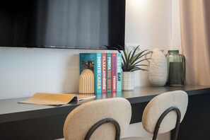 A modern room with a flat-screen TV mounted on the wall, a small potted plant, decorative vases, and a row of books on a shelf. - Downtown Bucharest Studio Close to Cismigiu & Universitatii (Bucharest)