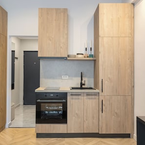 A compact kitchen with wooden cabinetry, a built-in oven, and a sink.