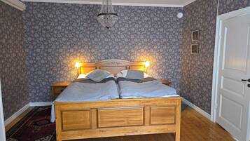 A bedroom with a wooden bed, floral wallpaper, and a chandelier.