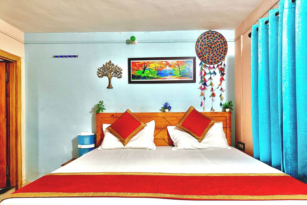 Una cama con cabecera de madera, ropa de cama blanca y detalles en rojo y dorado.