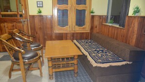 A wooden dining area with a table and chairs, a sofa, and a patterned rug.