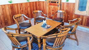 A wooden-paneled room with a round table and six chairs, each with a cushioned seat.
