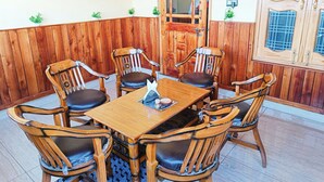 A dining area with a wooden table and chairs, a wooden door, and a window with a view.