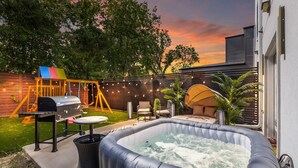 An outdoor patio with a hot tub, a barbecue grill, and a swing set. - Spacious 4-bedroom house in lovely Dallas W/Game room & Spa (Dallas)