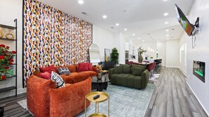 A modern living room with a patterned wall, a sofa set, a coffee table, and a dining area in the background. - Spacious 4-bedroom house in lovely Dallas W/Game room & Spa (Dallas)
