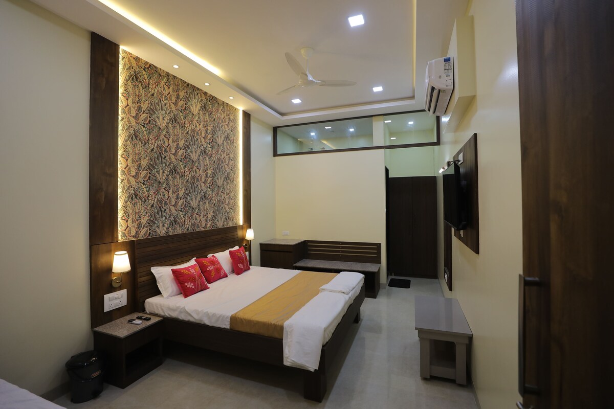 A modern hotel room with a large bed, bedside tables, a wall-mounted TV, and a ceiling fan.