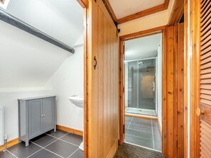 A bathroom with a grey cabinet, a white sink, and a shower area with a glass door.