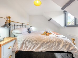 Un dormitorio con cama, mesita de noche, lámpara y bandeja para el desayuno.