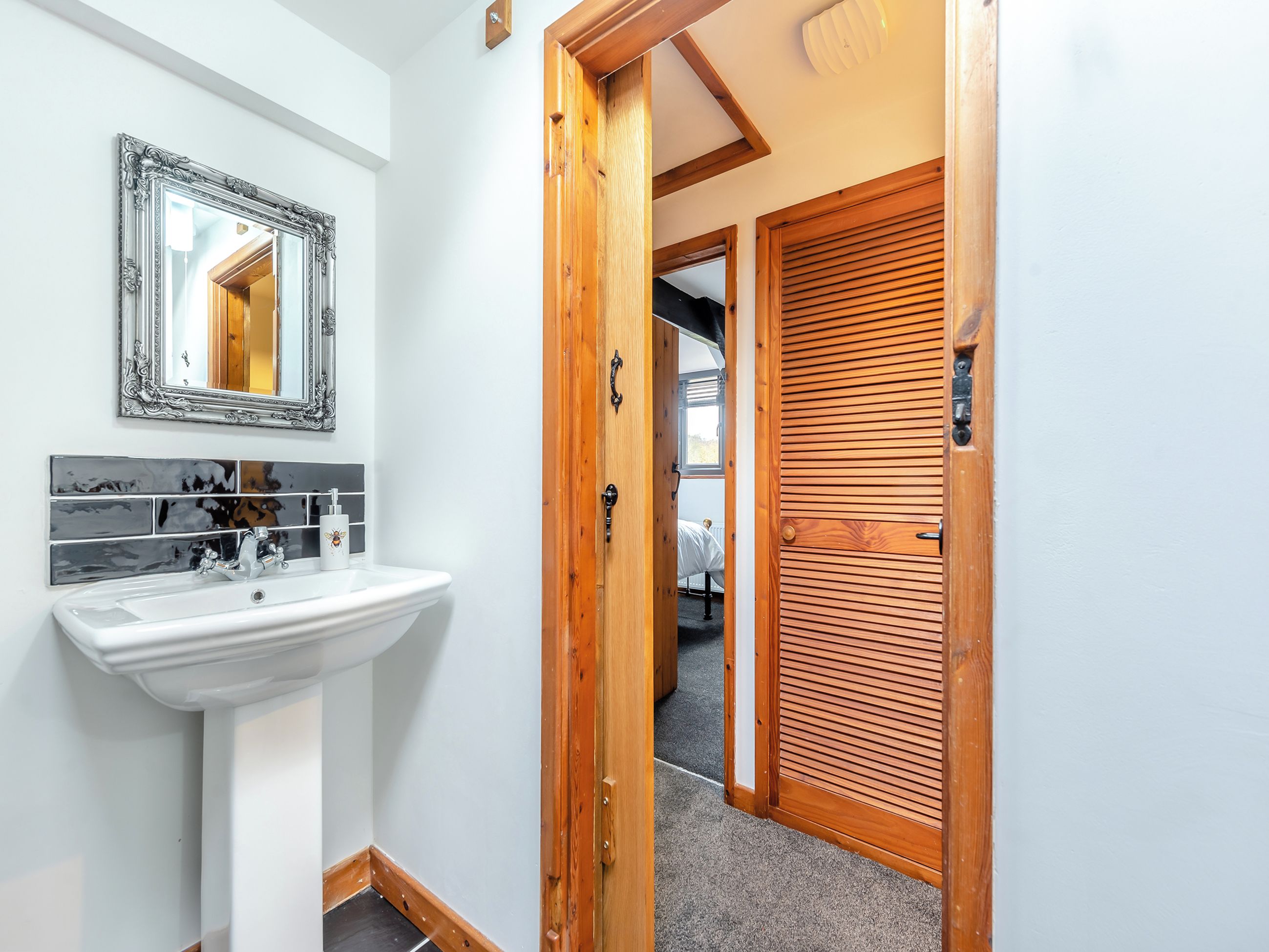 A bathroom with a white sink, a mirror with an ornate frame, and a tiled backsplash.