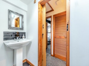 A bathroom with a white sink, a mirror with an ornate frame, and a tiled backsplash. - Cwtch Honey - UK49792 (Cribyn, Lampeter)
