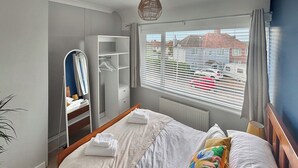 Une chambre bien rangée, avec un grand lit, une armoire et une fenêtre équipée de stores.