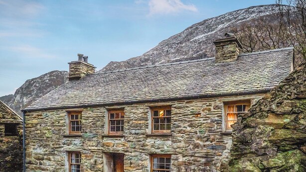 A stone house with a sloped roof, multiple windows, and a stone chimney. - 4 bedroom accommodation in Betws Garmon, near Beddgelert (Betws Garmon, near Beddgelert)