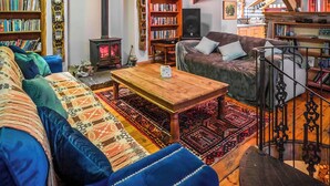A cozy living room with a sofa, a wooden coffee table, and a fireplace. There are bookshelves filled with books and a television. - 4 bedroom accommodation in Betws Garmon, near Beddgelert (Betws Garmon, near Beddgelert)