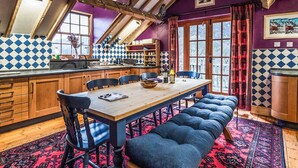 A dining area with a long wooden table, blue upholstered benches, and a patterned rug. - 4 bedroom accommodation in Betws Garmon, near Beddgelert (Betws Garmon, near Beddgelert)