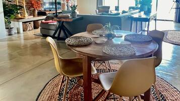 Un coin repas avec une table ronde, des chaises et des sets de table en fibres tressées.