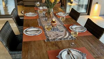 Une table à manger dressée avec des assiettes, des couverts et des verres, et un vase de fleurs et des bougies placés au centre.