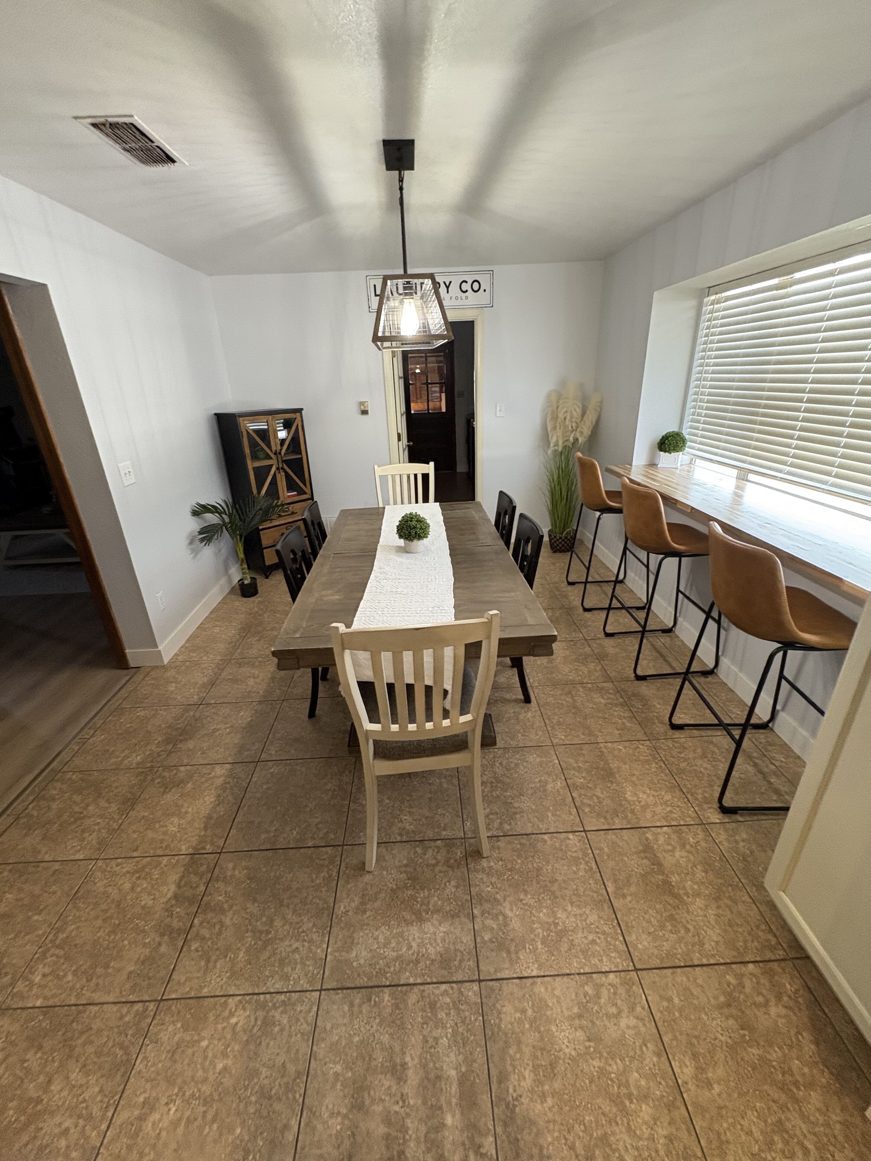 Un espace repas comprenant une longue table, des chaises et un luminaire suspendu.