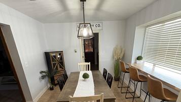Zona pranzo con un tavolo lungo, sedie e una lampada a sospensione.