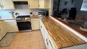 Een moderne keuken met witte kasten, een houten aanrecht, een fornuis en een magnetron.