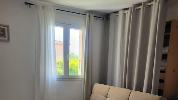 Une chambre d’hôtel avec un lit, un canapé, une petite table et une fenêtre avec des rideaux.