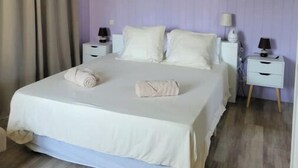 Une chambre à coucher comprenant un lit, deux tables de chevet, un ventilateur de plafond et un appareil de climatisation.
