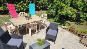 Une terrasse extérieure avec une table et des chaises, entourée de plantes en pot.