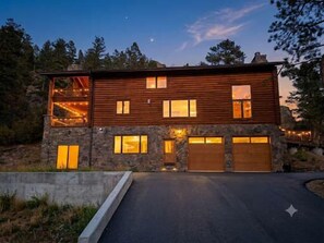 Una casa moderna de dos pisos con fachada de piedra, ventanas grandes y un garaje.