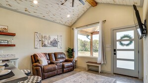 A cozy living room with a leather sofa, a coffee table, and a patterned rug. - Recently Built Cabin w/ Pavilion in Granbury! (Granbury)