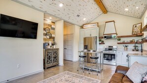 A modern kitchen with a built-in oven, a refrigerator, and a bar area with stools. - Recently Built Cabin w/ Pavilion in Granbury! (Granbury)