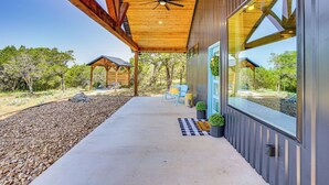 A modern building with a covered porch, large windows, and a ceiling fan. - Recently Built Cabin w/ Pavilion in Granbury! (Granbury)