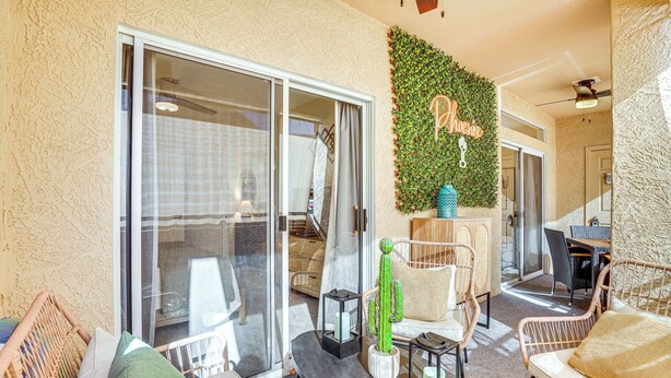 A spacious patio with sliding glass doors, wicker furniture, and a cactus centerpiece. - Family-Friendly Condo w/ Pool Access in Phoenix! (Phoenix)