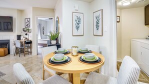 A dining area with a round table set for four, surrounded by chairs. There is a kitchen area to the left with a counter and a sink. - Family-Friendly Condo w/ Pool Access in Phoenix! (Phoenix)