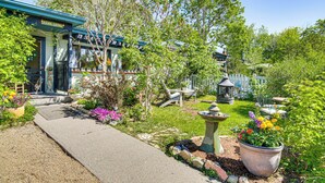 A cottage-style building with a pathway leading to the entrance, surrounded by lush greenery and various potted plants. - Walk to Dtwn Livingston: Studio w/ Mtn Views! (Livingston)