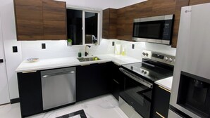 Una cocina moderna con lavavajillas, estufa, microondas y armarios de madera.