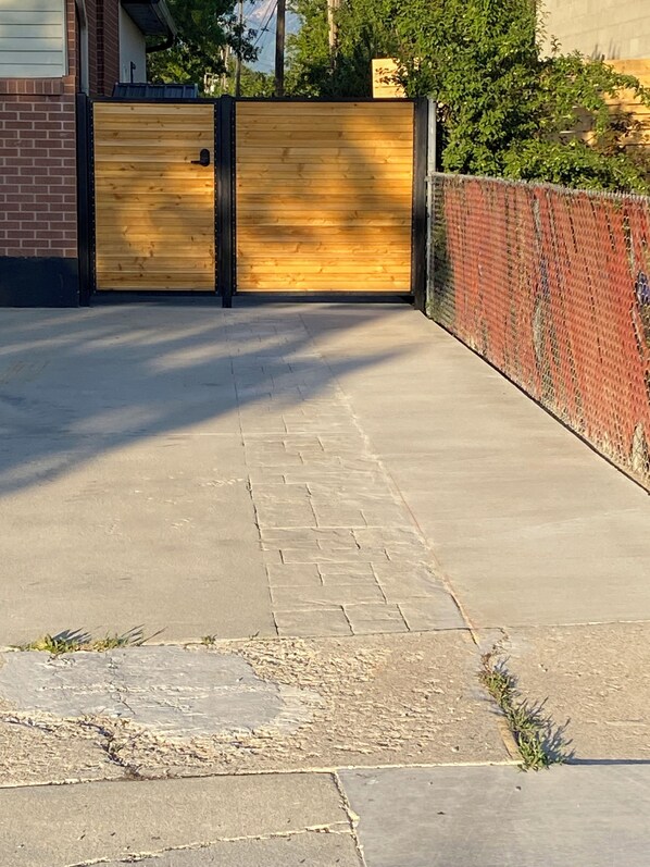 A paved driveway leading to a wooden garage door with a black frame.