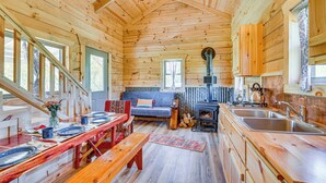 Ein Holzblockhaus mit Essbereich, Sofa, Küche und Kamin.