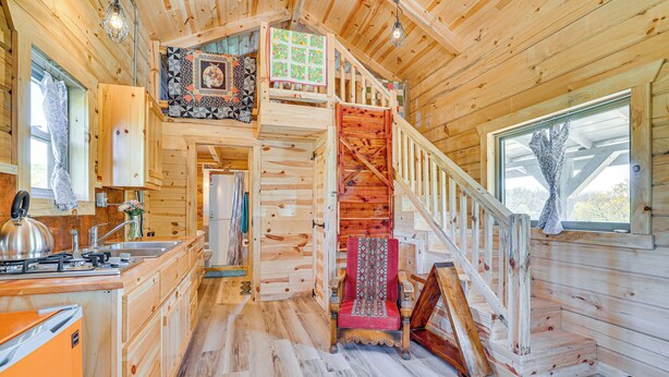 Ein Holzblock-Innenraum mit Küche, Essbereich und einer Treppe, die zu einem Schlafzimmerboden führt.