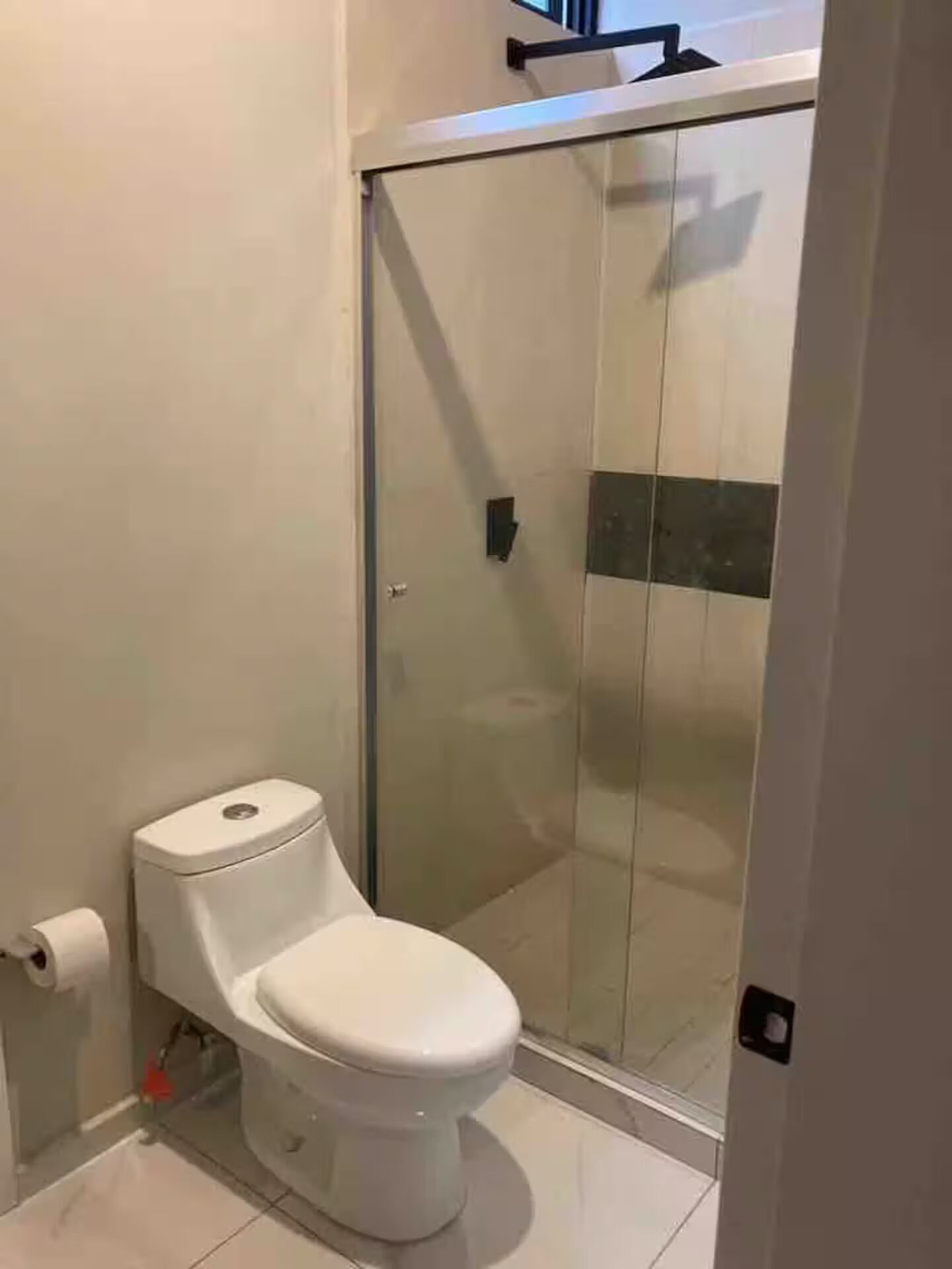 Ein Badezimmer mit Toilette, Duschkabine und Toilettenpapierhalter.