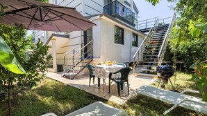 Une terrasse extérieure avec une table, des chaises et un barbecue.