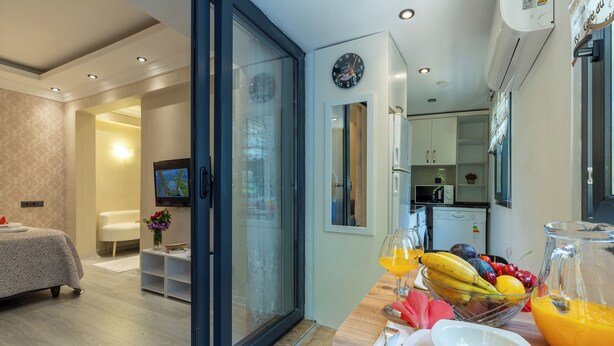 Une chambre d’hôtel moderne comprenant un coin repas, un lit et une cuisine visible à travers une porte ouverte.