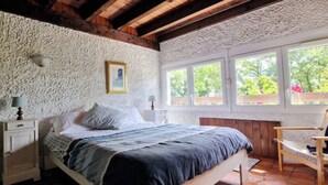 A bedroom with a bed, a chair, a window, and a textured wall. - Large campane house (Brignac-la-Plaine)