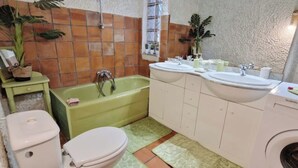 A bathroom with a green bathtub, two sinks, a toilet, and a washing machine. - Large campane house (Brignac-la-Plaine)