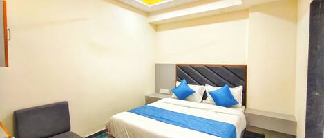 A hotel room with a bed, a chair, a ceiling fan, and an air conditioning unit.